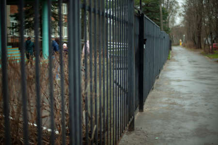 Black fence along the road. A fence encloses the building. Metal structure protects the territory.の写真素材