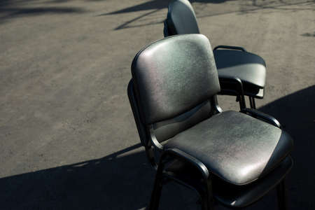 Black chairs stand outside. Office furniture in black. Sitting in sunlight.の写真素材