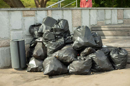 Garbage bags on the street. Black waste bags. Plastic bags with household waste collected in the park. Many sacks are piled up in the trash heap.の写真素材