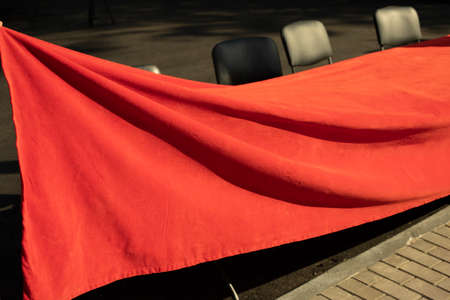 The red fabric is stretched over the table. Table cover. Preparation of street ceremonial. Solemn fabric.の写真素材