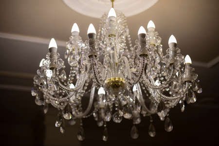 Glass chandelier. Ceiling light source. Lamps shine through a vintage chandelier.の写真素材