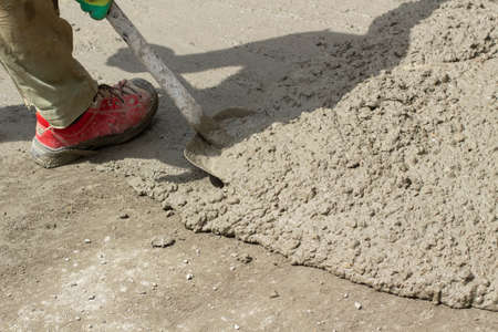 Cement on the road. Cleaning the cement with a shovel. Construction solution on the construction site. A hedgehog made of sand.の写真素材