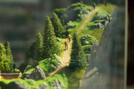 Miniature model of tourists on a mountain trail. Figures of people walking through the mountains. The atmosphere of a tourist trip is made in the form of a layout.の写真素材