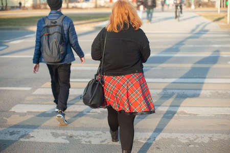 A girl in a red skirt walks through the city. The girl and the guy are walking on the street. Young people explore the city on foot.の写真素材