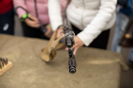 The girl disassembles the firearm. Automatic weapons of the Soviet Union. The student removes the barrel of the gun.の写真素材