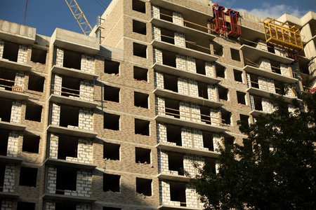 Construction of a building in the city. Unfinished house with empty windows. Brick structure.の写真素材