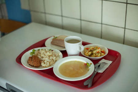 Food in the dining room. Lunch on a tray. Regular school meals. Meals for schoolchildren in Russia. Hot with compote in a glass.の写真素材