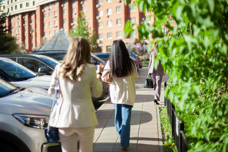 Girls in the summer go down the street in suits. The girls are walking around the city. People in the summer in the residential area.の写真素材