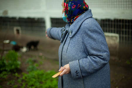 An old woman in Russia. Pensioner in a coat on the street. A woman in a headscarf on her head.の写真素材