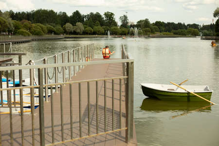 Boat on the pier. Boat station on the city pond. A pier for those wishing to swim on a boat on the lake in the park.の写真素材