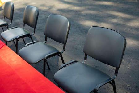 Office chairs stand in a row. Black chairs for seating guests. Empty seats at the table. Prepared celebration. Summer residence.の写真素材