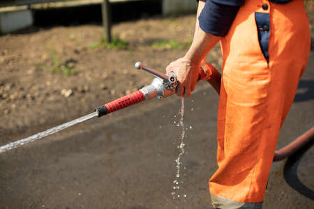 Water hose. The flow of water from the pipe. A man holds a fire hose.の写真素材