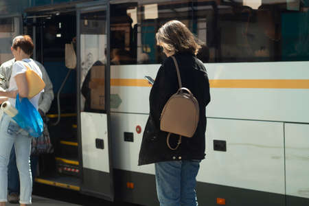 People at the bus stop. Waiting for transport. People stand by the road in the summer waiting for the bus.の写真素材