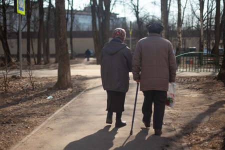Two pensioners are walking down the street. Grandmothers photographed from the back. Elderly women are walking down the street. Old people walk in the afternoon. Footpath.の写真素材
