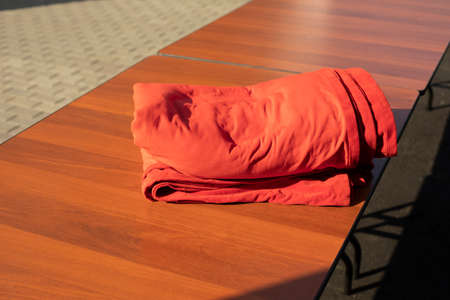 Red fabric lies on the table. Material to cover the table. Tablecloth on the face. A folded piece of red matter. The fabric is crutly.の写真素材