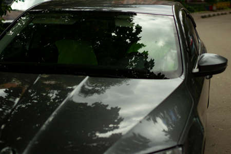 The car is in the parking lot. The surface of the transport. The car is in the shadows. Hood and roof. Reflections on the glossy surface of the car.の写真素材