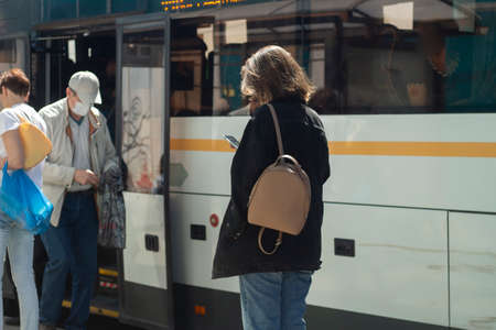 People at the bus stop. Waiting for transport. People stand by the road in the summer waiting for the bus.の写真素材