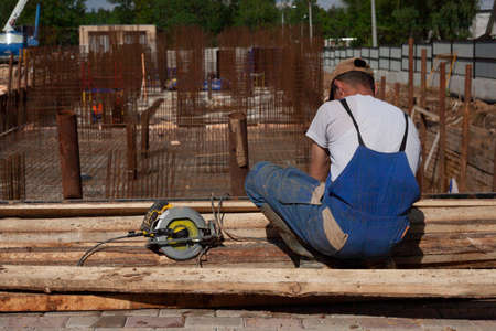 The builder is doing the job. Repair of the fountain in the park. A man in overalls with an electric saw.の写真素材