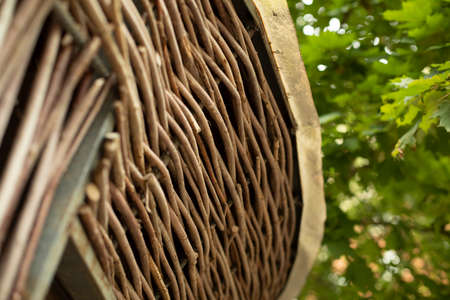 Braided plant twigs. Details of the veranda. Background summer building on the street. Park architecture shot close.の写真素材