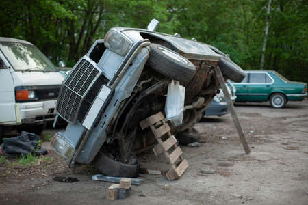 The old car is being repaired. The machine has been lifted to inspect the underbody. The car has been lifted with improvised means.の写真素材