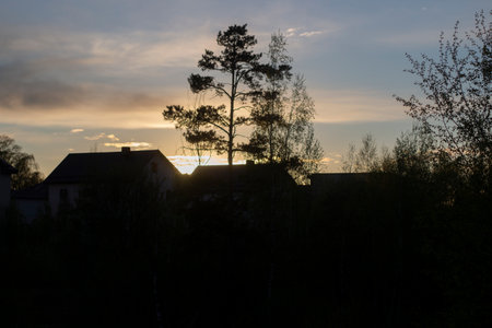 Silhouettes of houses and trees at sunset. Sunset in the countryside. Evening sky and at home.の写真素材