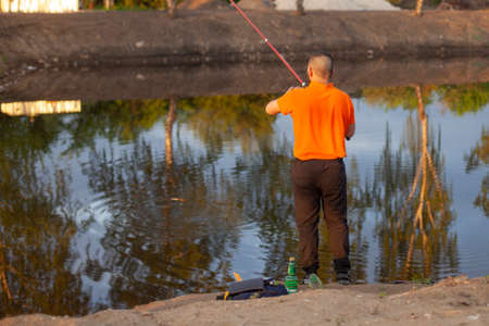Men are fishing. The guys are fishing with a line. Fishing at sunset on a small pond.の写真素材
