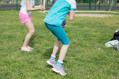Children are dancing on the lawn. The girls are filming and dancing. Jumping girls on a hot day. Children are having fun. Shooting without faces.の写真素材