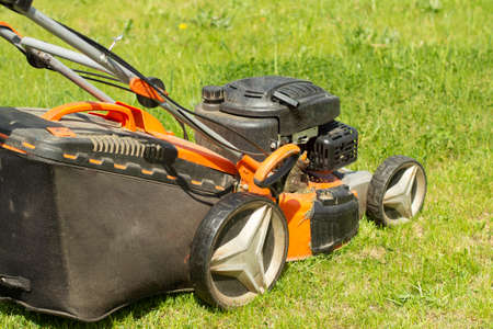 A lawn mower cuts the grass. A lawnmower shaves the lawn. Gardener's job. Lawn care.の写真素材