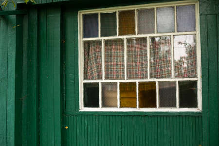 An old window in the village. Colored glass in the window frame. Facade of the house. Country house with white window.の写真素材