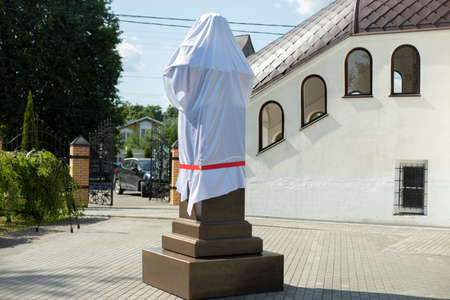 Closed monument. Opening of the monument on the street. White fabric on a bronze pedestal.の写真素材
