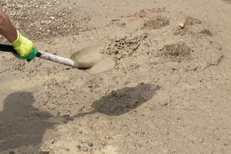 Shovel with sand. Throws sand with a shovel. Work at a construction site. Removing dirt from the road.の写真素材
