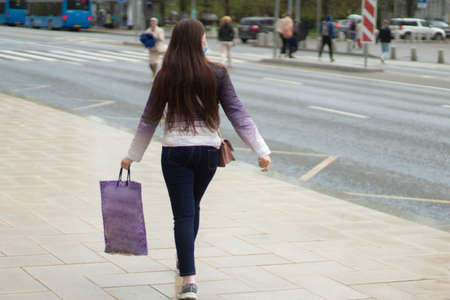 The girl with the bag on the street. The girl rushes to the bus on the street. A woman is in a hurry to work.の写真素材