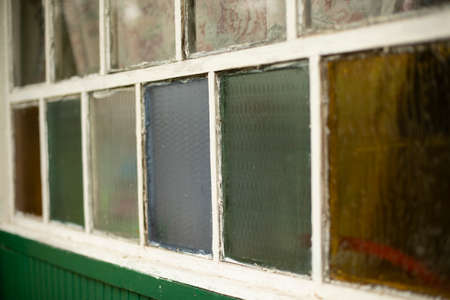 An old window in the village. Colored glass in the window frame. Facade of the house. Country house with white window.の写真素材