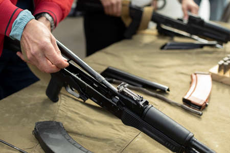 A man disassembles a firearm. A person undergoes military training. Cleaning the barrel of the machine. Soviet firearms. Shooting lesson in detail.の写真素材