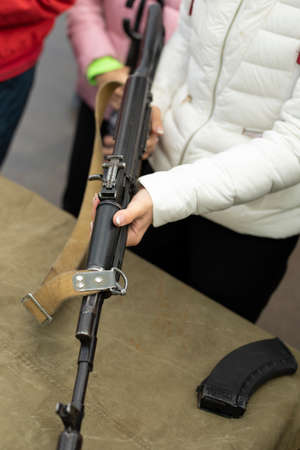 The girl disassembles the firearm. Automatic weapons of the Soviet Union. The student removes the barrel of the gun.の写真素材