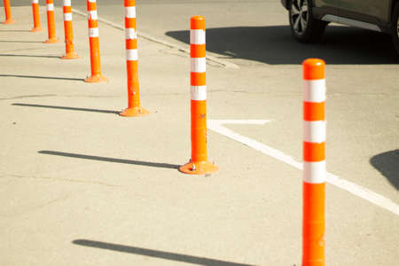 Parking stops. Orange posts in the parking lot. Carriageway fencing. The place of unloading of freight transport is fenced with high posts.の写真素材
