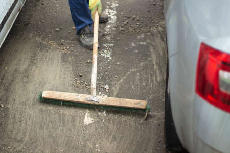 Cleaning the parking lot with a broom. Dirty asphalt in the yard. A worker cleans the road.の写真素材