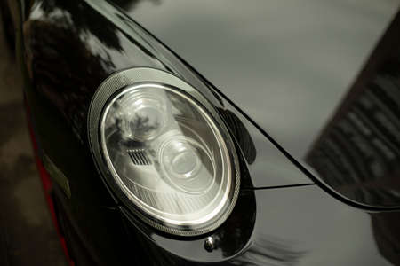 Car headlight. Black car with white headlight. Vehicle body parts. Machine lights.の写真素材