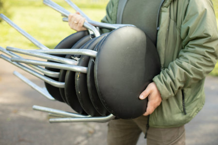 A man carries chairs. Lots of chairs in hand. Furniture on the street. Moving office furniture.の写真素材