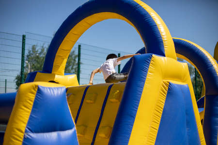 Children climb an inflatable slide. Inflatable obstacle course for fun. Active rest for children. Inflatable playground. Sports and fun.の写真素材