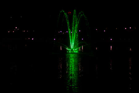 Colored fountain at night. Colored fountain on the pond. The streams of water are highlighted with a colored fan.の写真素材