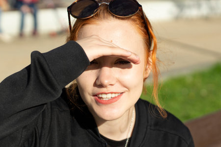The girl hides her eyes from the bright sun. The schoolgirl made a visor from the light out of her...