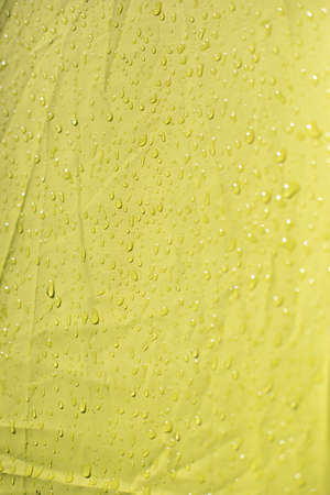 Wet cloth. Drops on yellow fabric. Wet awning from the rain.の写真素材
