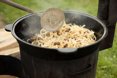 Cooking pilaf. The food is fried in a frying pan. Lunch in nature. National Uzbek dish pilaf.の写真素材