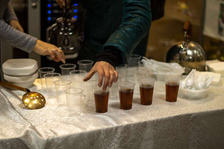 A man takes hot tea. Handing out tea to the poor. Hot drink on the table. The hand reaches for the glass.の写真素材