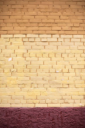 Brick wall painted with yellow paint. The texture of the wall of the building. Painted surface of the house.の写真素材