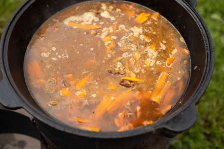 Soup in a pot. Food outside. Cooking soup on an open fire. National dish. Fatty food.の写真素材