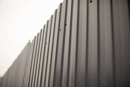 Gray fence made of metal. Solid high fence. Profiled metal is used in the fence of private territory. Ribbed surface.の写真素材