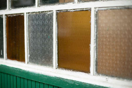 An old window in the village. Colored glass in the window frame. Facade of the house. Country house with white window.の写真素材