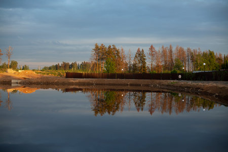 A pond excavated in the city. Water and shore. The lake at sunset. The land around the pond.の写真素材
